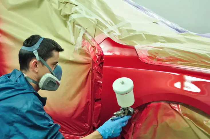 Worker painting car