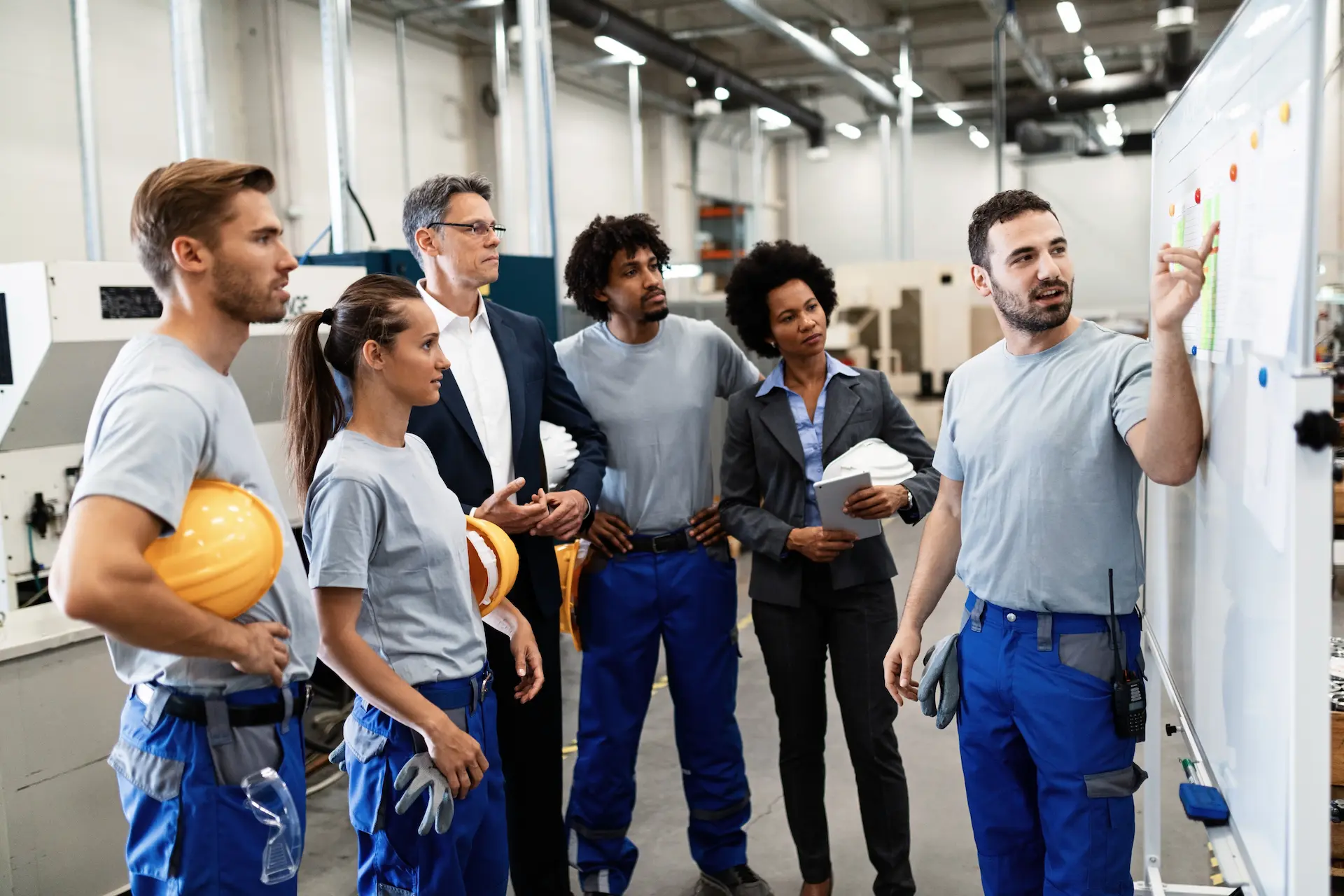 High-Volume job employees on first briefing during first week of work looking at manager explaining things infront of white board