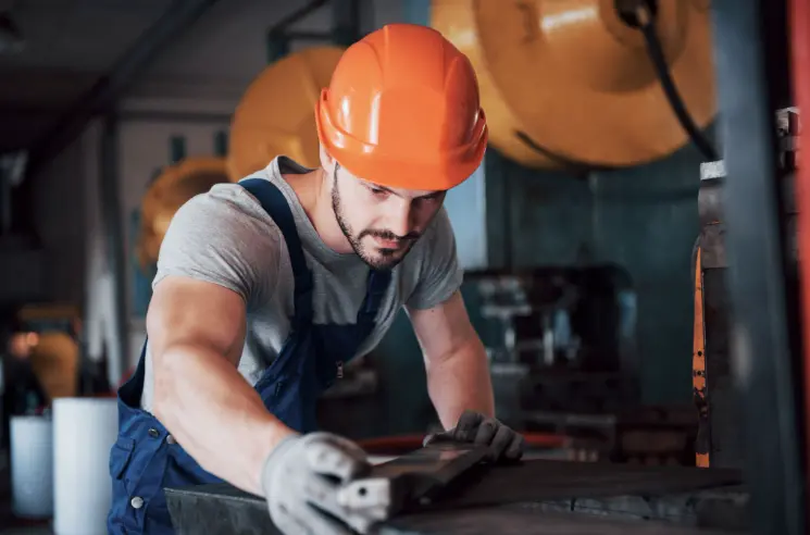 Woodworker working in factory with safety gear on