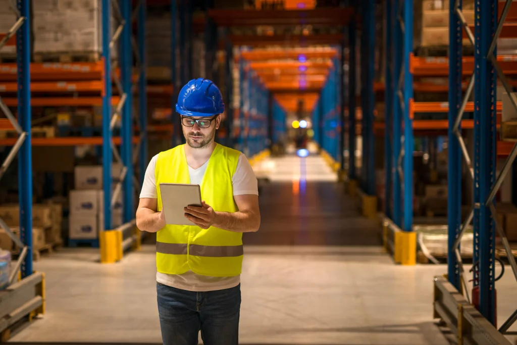 man walking through large warehouse storage storehouse center using tablet control distribution