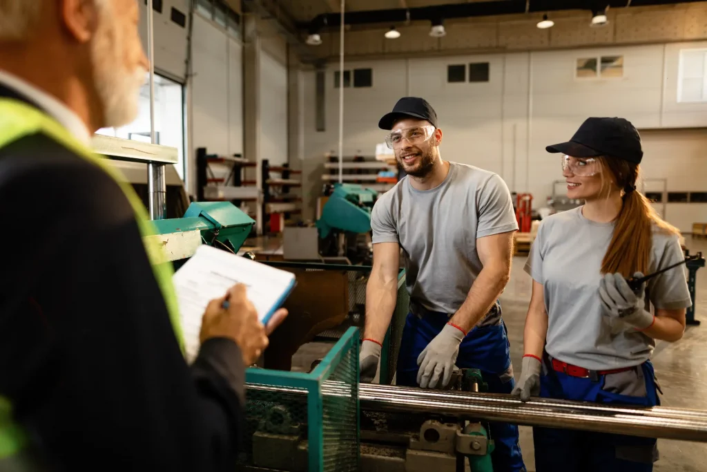 two happy workers working machine communicating with senior businessman who is overseeing them