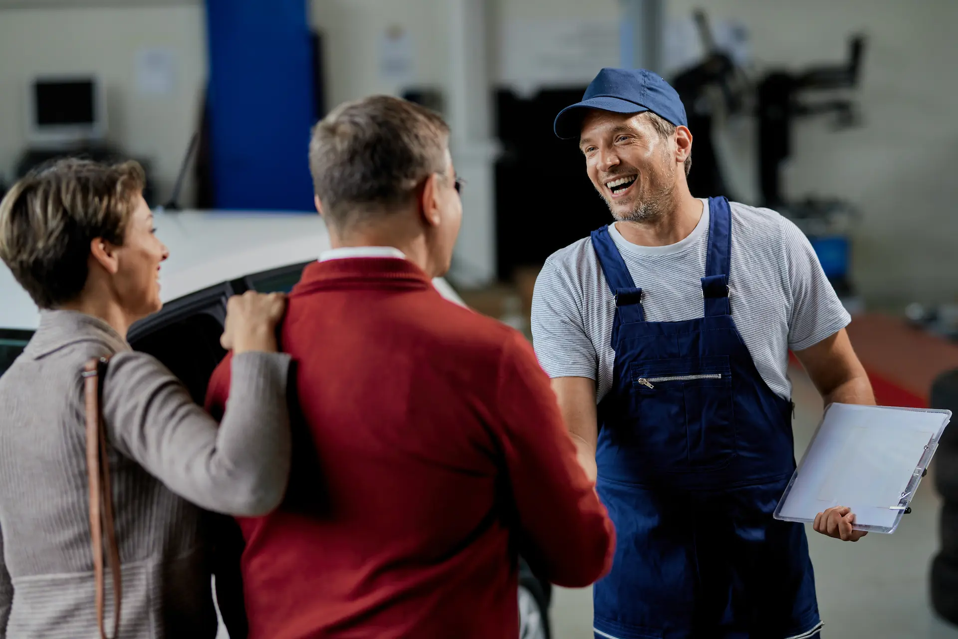 happy auto repairman shaking hands with recruiters workshop
